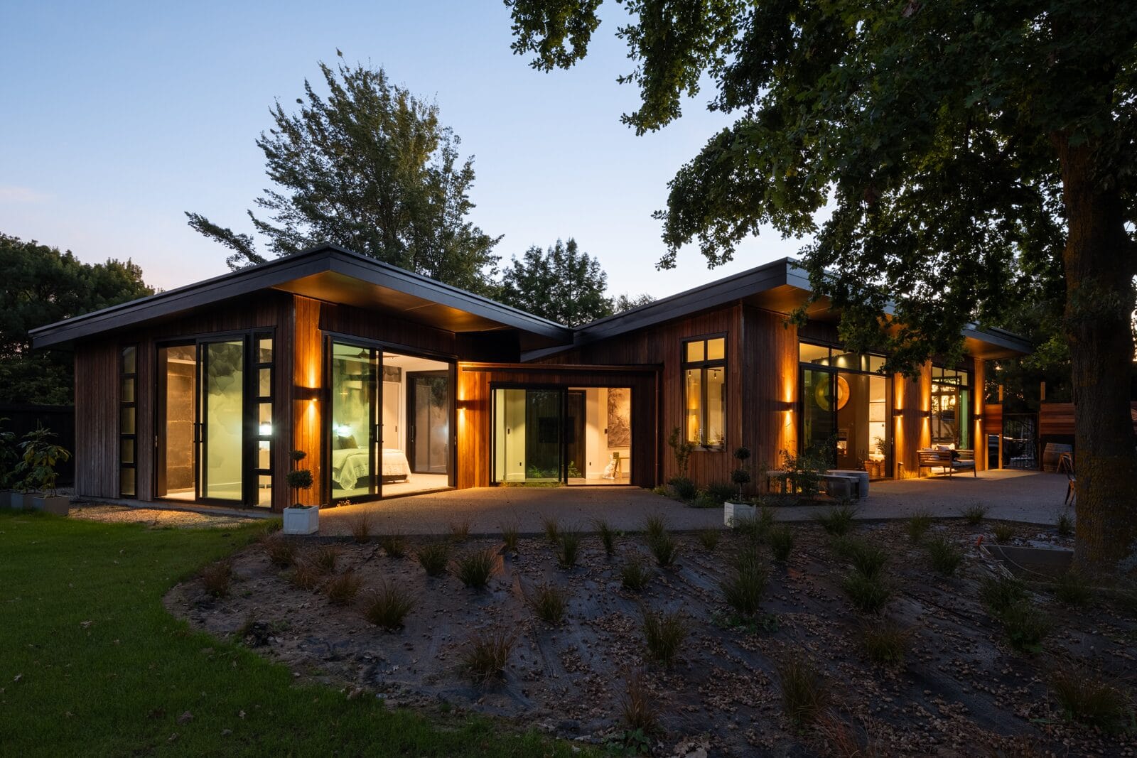 Custom Discovery Homes new build at dusk, with cedar cladding and warm interior lighting