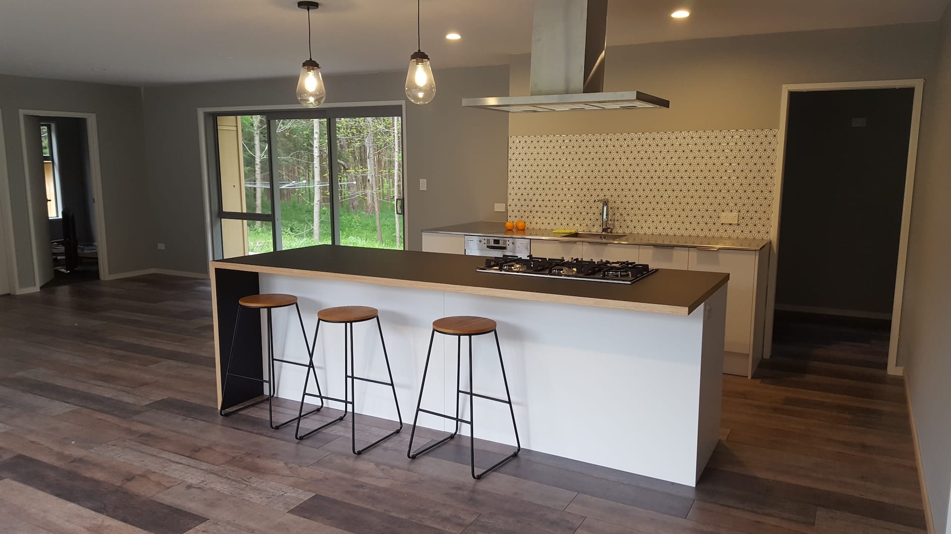 White island kitchen with patterned tile splashback and gas cooktop