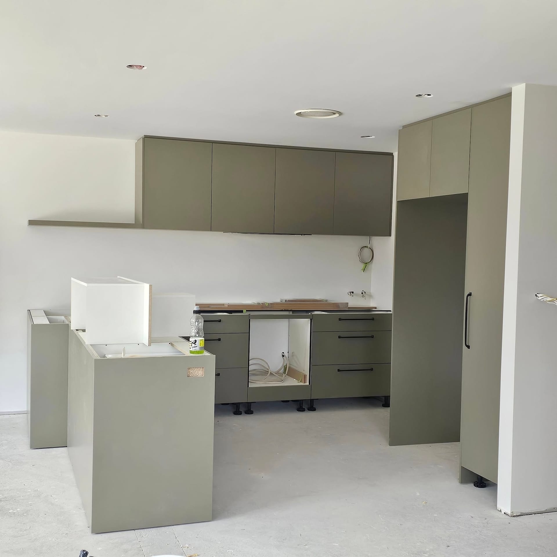 Sage green kitchen mid-installation, custom joinery being fitted