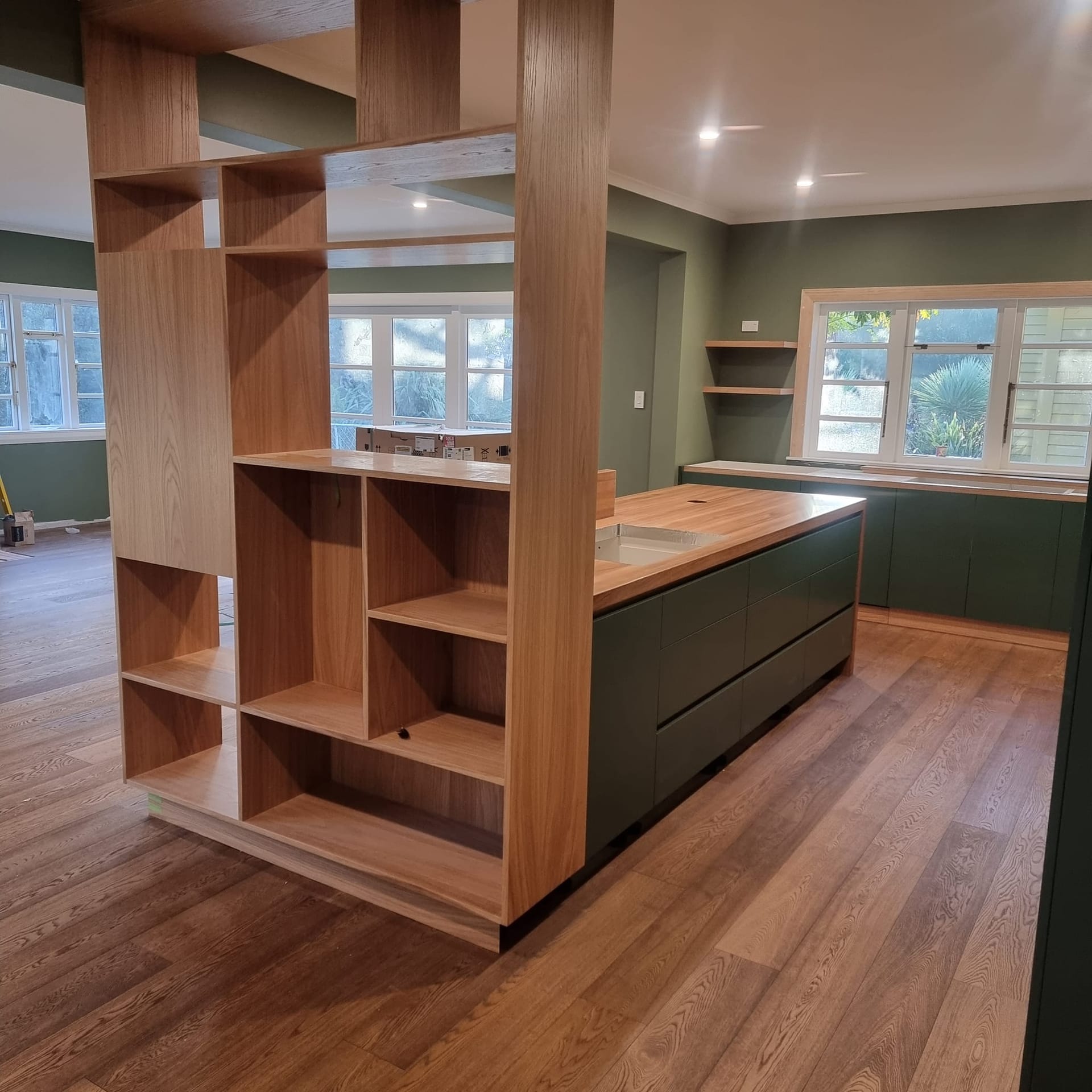 Smalls renovation kitchen with deep green joinery and oak shelving divider