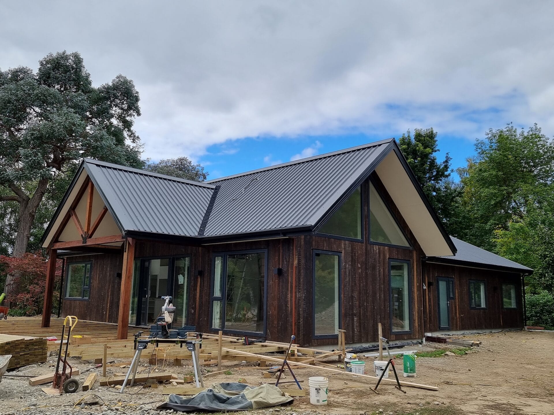McLean Home — exposed Spotted Gum A-frame trusses and dark vertical board cladding under construction