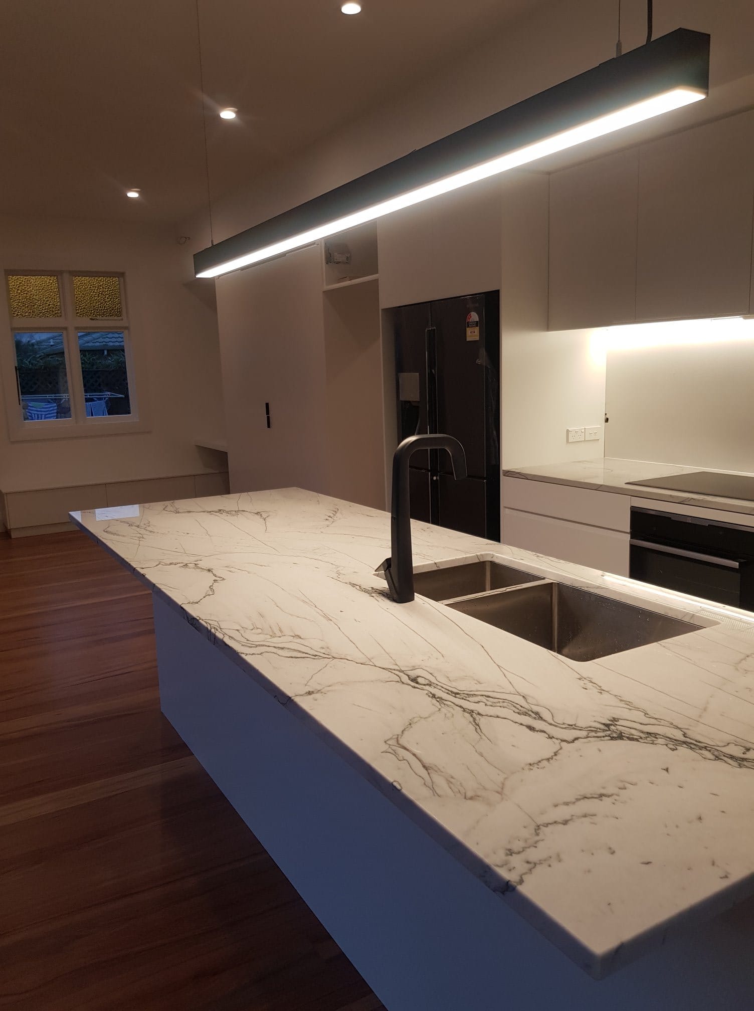 Renovated kitchen with marble island, modern lighting, and timber floors